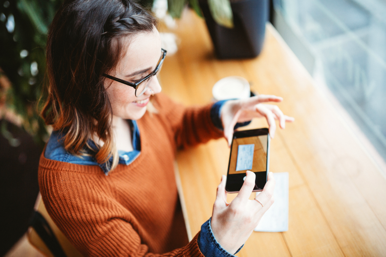 Woman using a mobile phone to deposit a paper check