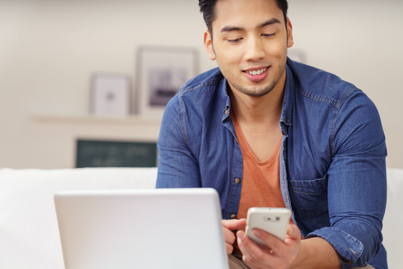 Man on his mobile phone in front of his laptop computer
