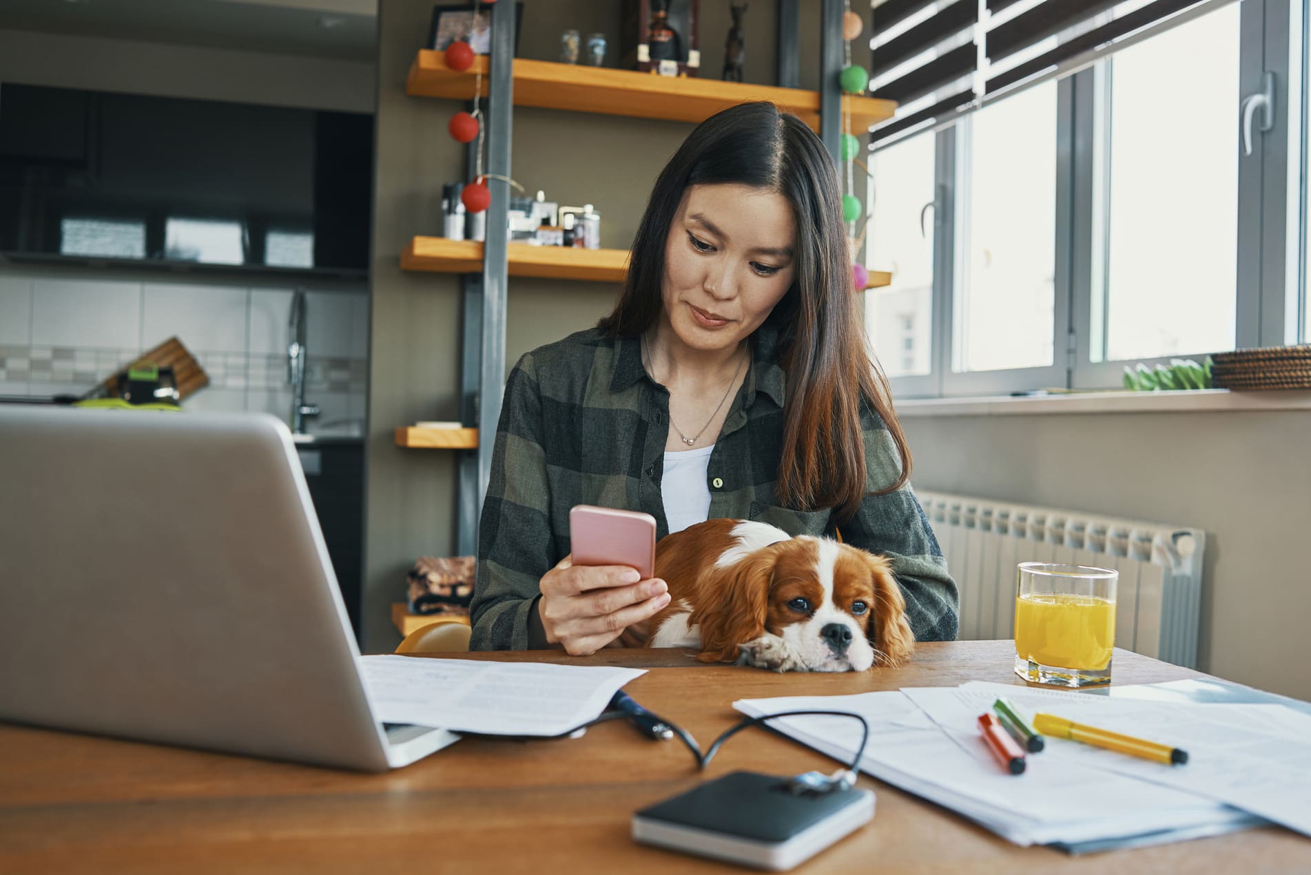 Woman at table with laptop looking at mobile