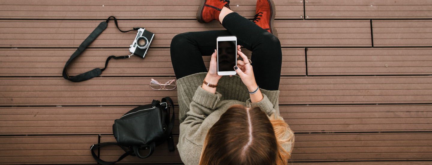 woman sitting on deck looking at mobile with camera