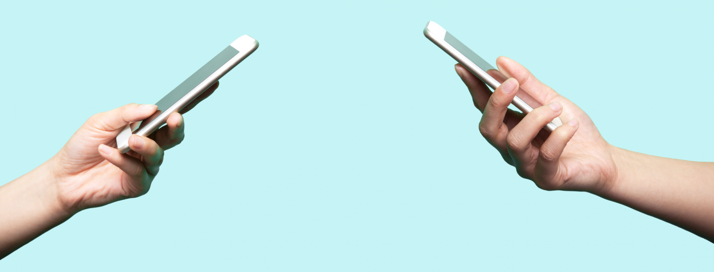 two hands holding iphones facing each other