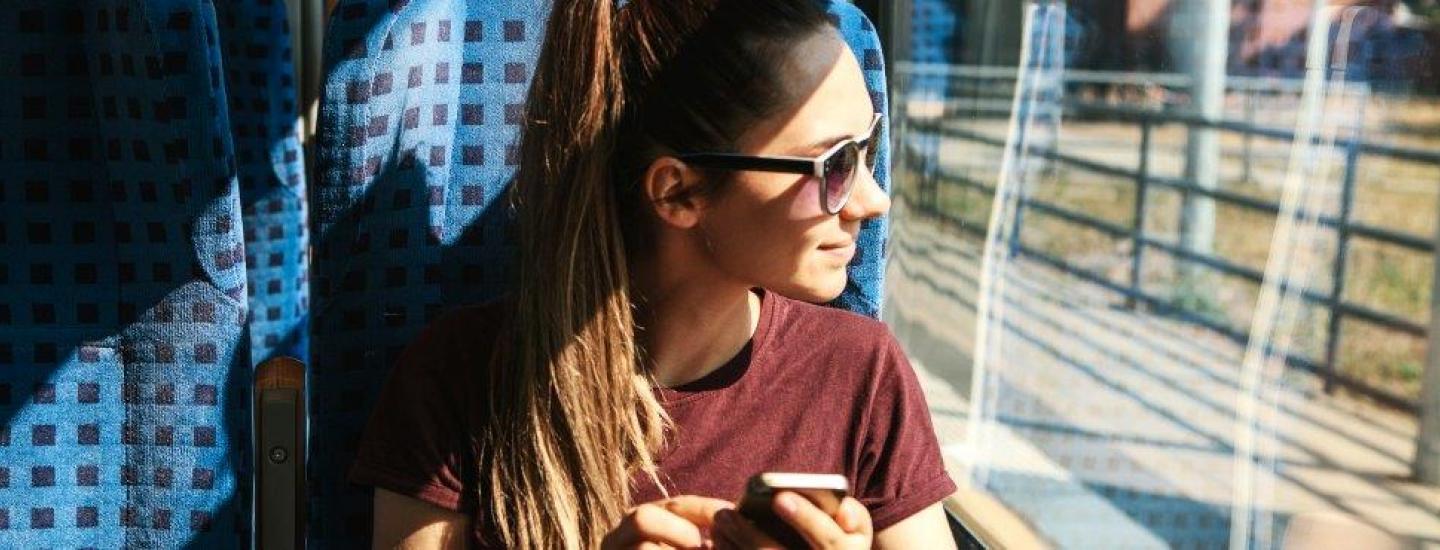 Woman on train with her phone out. 