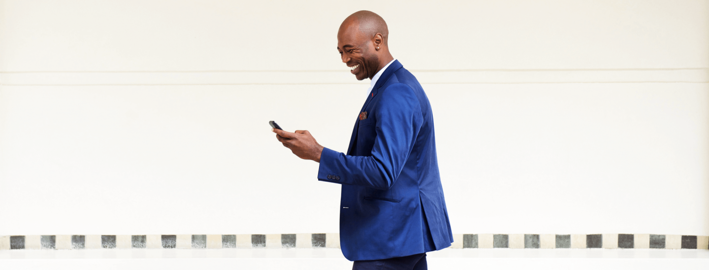 Man smiling as he stares at his phone.