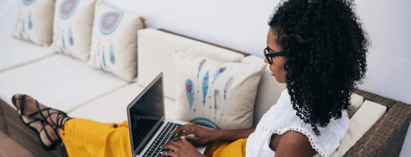 Woman working while laying on couch.