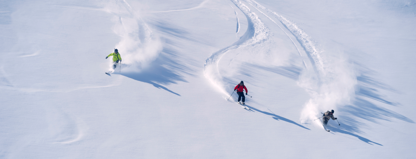 Three people going down the slope on their skis