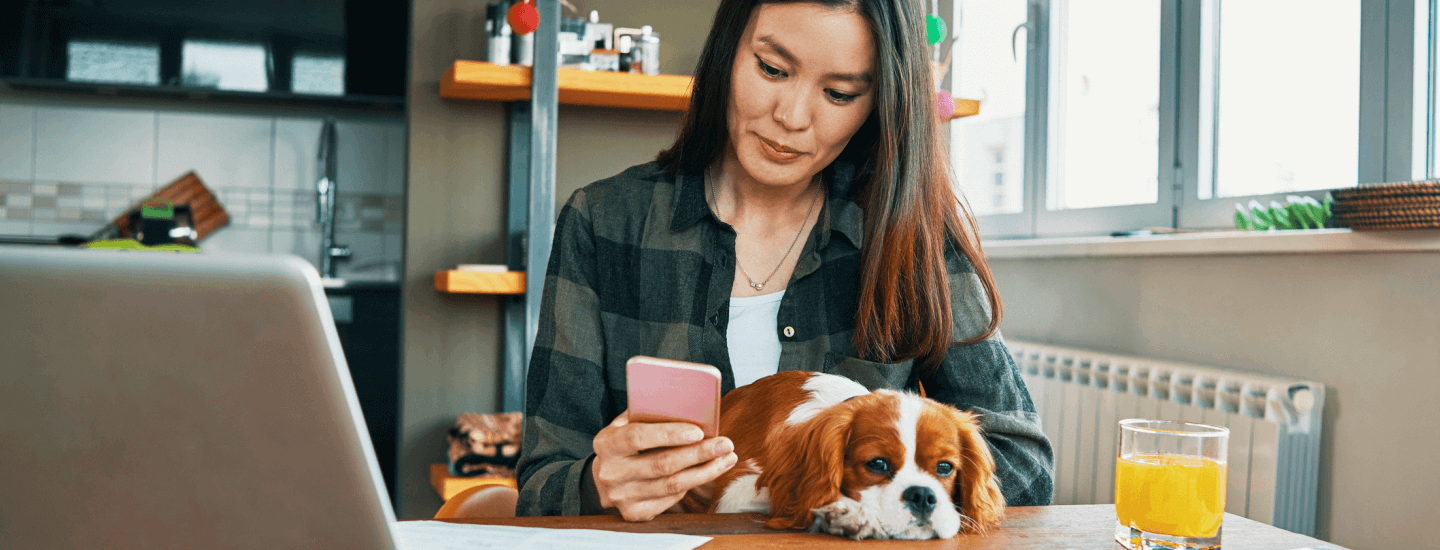 Woman petting dog and looking at her phone.