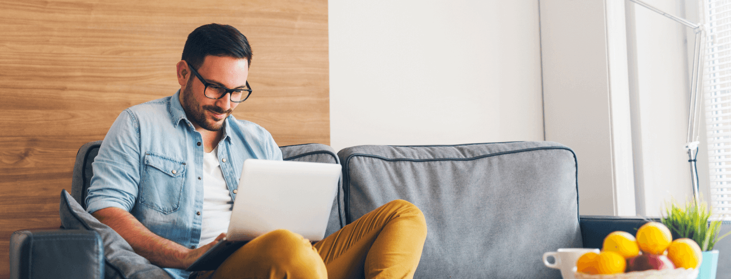 Man sitting on couch using his laptop.