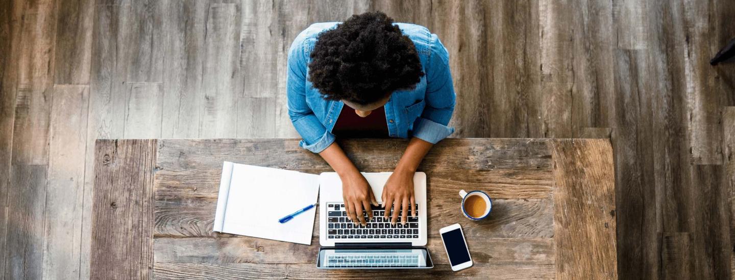 Woman works at table on laptop