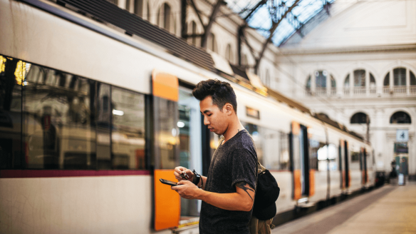Man uses phone standing at train station